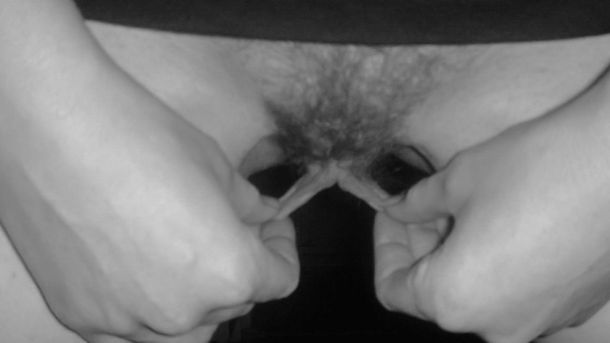 Woman with pubic hair stretching her labia minora